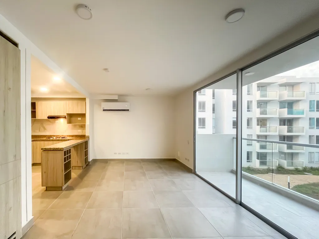 Sala social del apartaestudio con ventanal corredizo de piso a techo hacia el balcón privado